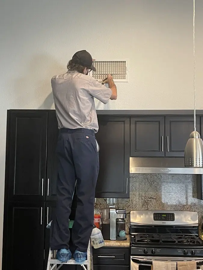 Technician inspecting an air vent during HVAC service in New Hanover